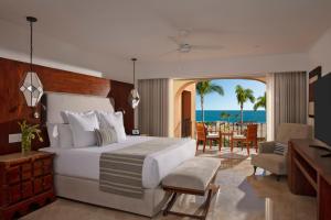 a bedroom with a bed and a dining room with the ocean at Zoetry Casa del Mar Los Cabos in Cabo San Lucas