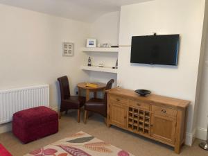 Una sala de estar con televisión, mesa y sillas. en Apartment 8 The Landings, en Filey