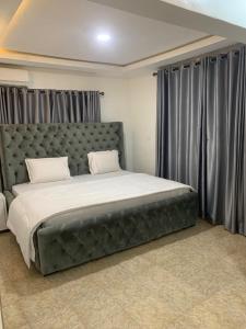 ein Schlafzimmer mit einem großen Bett mit grauen Vorhängen in der Unterkunft Weena Hotel & Resort in Lagos