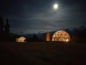 two domed buildings at night with the moon in the sky at La Meca Glamping in Guasca