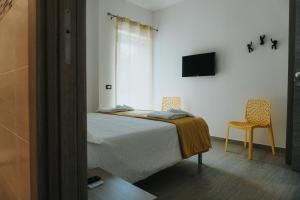 een slaapkamer met een bed en een tv en 2 stoelen bij Harmony Guest House in Leporano Marina