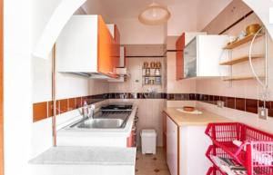 a small kitchen with white cabinets and red accents at Casa di Maria a Bosco in San Giovanni a Piro