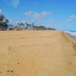 a sandy beach with a house in the distance at Villa Cocotiers A11 in Cotonou