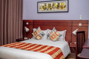 a bedroom with a bed with a blanket and pillows at Résidence Hôtelière Lauria in Lomé +85 photos