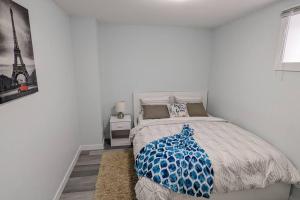 um quarto com uma cama com um cobertor azul em SERENE & MODERN 1BED SUITE + CLOSE TO AIRPORT em Regina