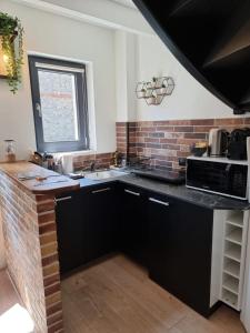 eine Küche mit schwarzen Schränken und einer Ziegelwand in der Unterkunft Rive Sud - Charmante Maisonette 2 P - Stadtzentrum in Honfleur
