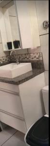 een witte badkamer met een wastafel en een toilet bij Flat & Residence Premium - Apês mobiliados e bem equipados in Campo Grande