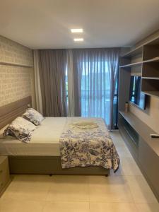 - une chambre avec un lit, une télévision et une fenêtre dans l'établissement Deluxe Cupe Beach Living, à Porto de Galinhas