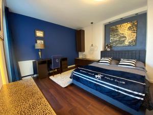 a bedroom with a blue wall and a bed with pillows at Apartament Transatlantyk in Gdynia