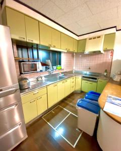 a kitchen with yellow cabinets and a stainless steel refrigerator at Holiday Cottage BANSHIRO in Setouchi