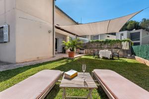 a garden with a bench and a table with a book at Villa Tamarells - Alcúdia in Alcudia