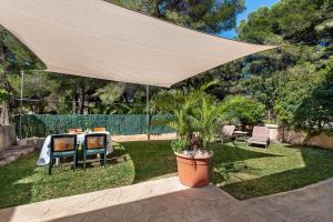 a patio with a table and chairs under a large umbrella at Villa Tamarells - Alcúdia in Alcudia