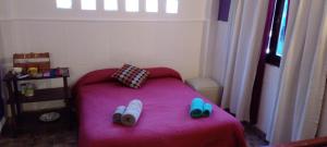 un dormitorio pequeño con una cama rosa con zapatos. en Habitación en casa con pileta en Río Ceballos en Río Ceballos