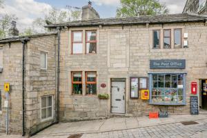 an old stone building with a sign that reads the best gifts at Weavers Cottage in Hebden Bridge