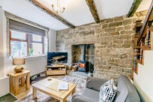a living room with a stone wall with a fireplace at Weavers Cottage in Hebden Bridge