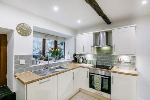 a kitchen with white cabinets and a sink at Weavers Cottage in Hebden Bridge