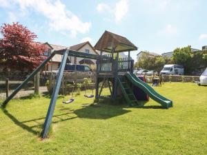 a playground with a slide in a yard at Beech Cottage in Benllech