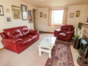 a living room with two red leather chairs and a coffee table at York Cottage in Wooler