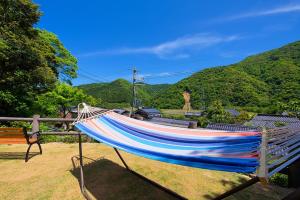 a hammock sitting in a field with mountains in the background at TABIHAKU STAY 香住 in Kasumi