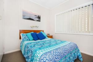 a bedroom with a bed with blue and white sheets at Boorolong 3 - Linen not provided in Yamba