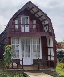 uma casa de madeira com um banco em frente em Villa Lorong Sempit Puncak 2000 Siosar em Pertibi