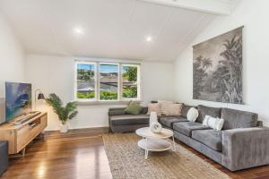 a living room with a couch and a tv at High Three - Downtown Beach House in Yamba