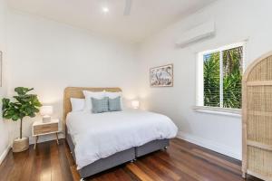 a white bedroom with a bed and a window at High Three - Downtown Beach House in Yamba