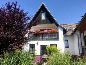 ein weißes Haus mit einem Balkon mit Blumen darauf in der Unterkunft Ferienwohnung 2 "Nettchen" Objekt ID 1205 in Waren (Müritz)