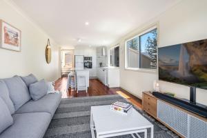 a living room with a couch and a tv at Seaspray 1 in Yamba