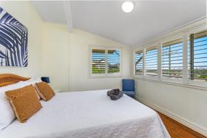 1 Schlafzimmer mit einem weißen Bett und 2 Fenstern in der Unterkunft The Beach House Nine in Yamba