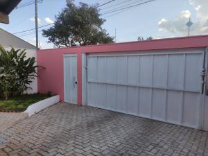 a garage with a pink and white building at Lindo quarto c/ banheiro privativo in Jaú