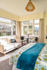 ein Schlafzimmer mit einem Bett, einem Sofa und Fenstern in der Unterkunft Sunny Mornington 2 Bedroom Guest Suite in Dunedin