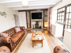 sala de estar con sofás de cuero y chimenea en Bank Cottage, en Alston