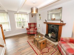 a living room with a fireplace and a red chair at Bank Cottage in Alston