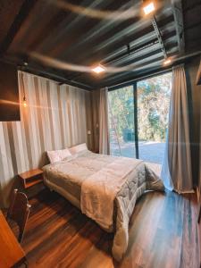 a bedroom with a bed and a large window at Container ABOBORA na natureza da Serra Gaúcha in Flores da Cunha