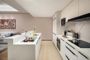 a kitchen with white cabinets and a counter with vegetables on it at Ascott M-City Foshan in Foshan