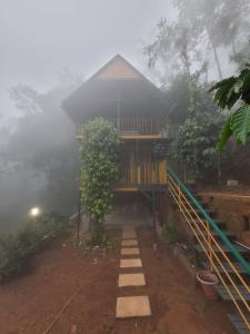 a house in the fog with a walkway in front of it at Mistvalley Hut in Chithragiri