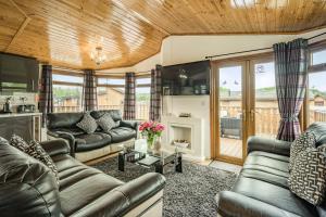 a living room with leather couches and a fireplace at Lakeview Lodge in Carnforth