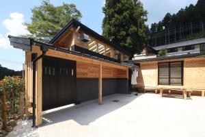 ein Haus mit einer Garage mit einer Bank davor in der Unterkunft 古民家ー芦ヶ久保 in Chichibu