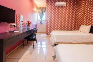 a room with two beds and a desk with a television at Value Inn Homestay in Butterworth