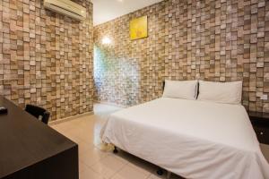 a bedroom with a bed and a brick wall at Value Inn Homestay in Butterworth