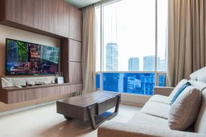 a living room with a couch and a tv with a large window at Soho Suites KLCC by GuestHouse in Kuala Lumpur