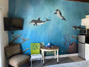 a room with a table and dolphin wall mural at Magic Beach Motel - Vilano Beach, Saint Augustine in Saint Augustine