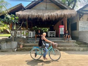 a man riding a bike in front of a building at Gita Gili Bungalow in Gili Islands