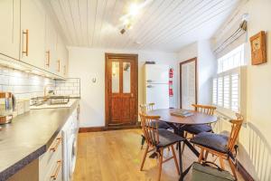 a kitchen with a table and chairs and a refrigerator at Saddlers Cottage in Matlock