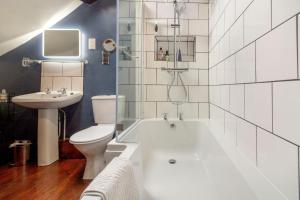 a bathroom with a tub and a toilet and a sink at Saddlers Cottage in Matlock