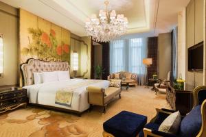 ein Schlafzimmer mit einem großen Bett und einem Kronleuchter in der Unterkunft Wanda Realm Chifeng Hotel in Chifeng