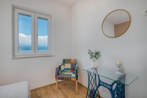 a glass table and a chair in a room with a mirror at Nevera 1 in Vrbnik