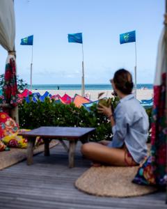 una mujer sentada en una mesa de picnic junto a la playa en Rancho Do Peixe, en Prea