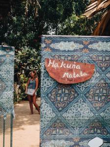 阿魯岡灣的住宿－Hakuna Matata Arugambay，站在一个没有黑头的标志旁的女人